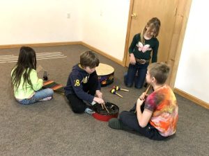 Four students play with different styles of drums.